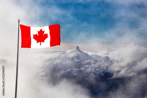 Aerial View of the Beautiful Canadian Nature Mountain Landscape during a cloudy and sunny winter day. Taken from the Peak of Whistler, British Columbia, Canada. With Flag composite