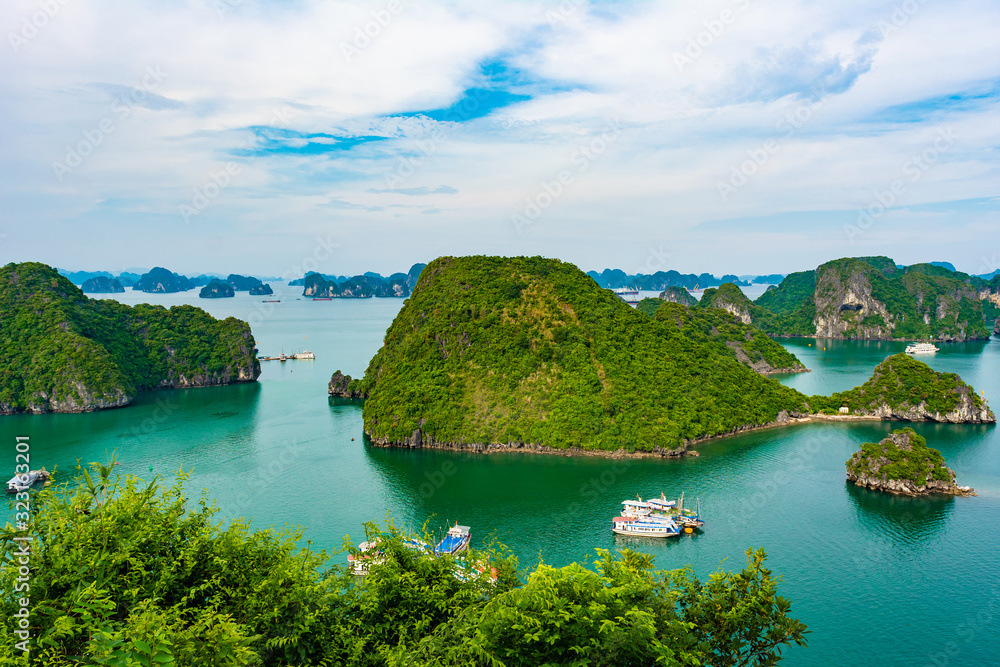 Aerial view of Ha Long Bay; with a lot of limestone islets and cruise ships; on a cloudy summer day.