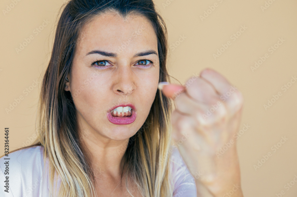 Angry aggressive lady threatening at camera. Dissatisfied mad young woman with crazy grimace showing fist. Rage concept Angry aggressive lady threatening at camera. Dissatisfied mad young woman with crazy grimace showing fist. Rage concept
