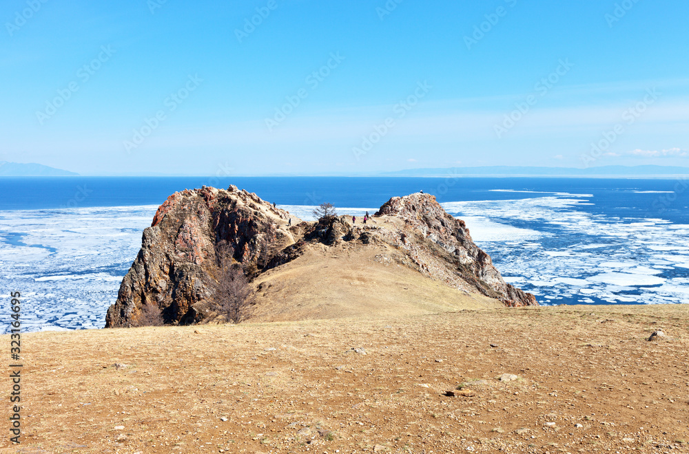 Baikal Lake in the May ice drift. A group of tourists travel around Olkhon Island and visit the famous Cape Shunte-Left or as it is called Cape of Love. Beautiful spring landscape, natural background