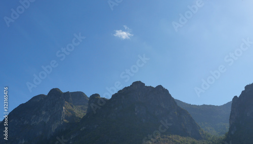 Limestone mountain in the morning light that shines from behind with blue sky and small white cloud in background , Khao Sam Roi Yot national park ,Thailand