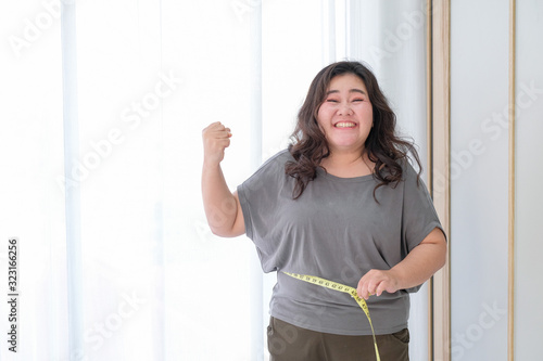Fotografie Asian obese women are happy because of size reduction after checking with tape measure