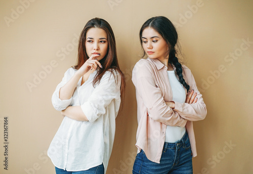 Canvas Print Young upset girls friends in casual offended at each other isolated on beige bac