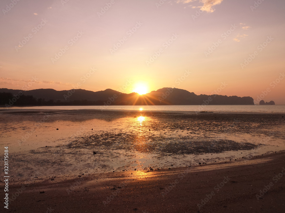 Exotic sunrise on a sandy beach with mountains in the background. Exotic sunrise on a sandy beach with mountains in the background.