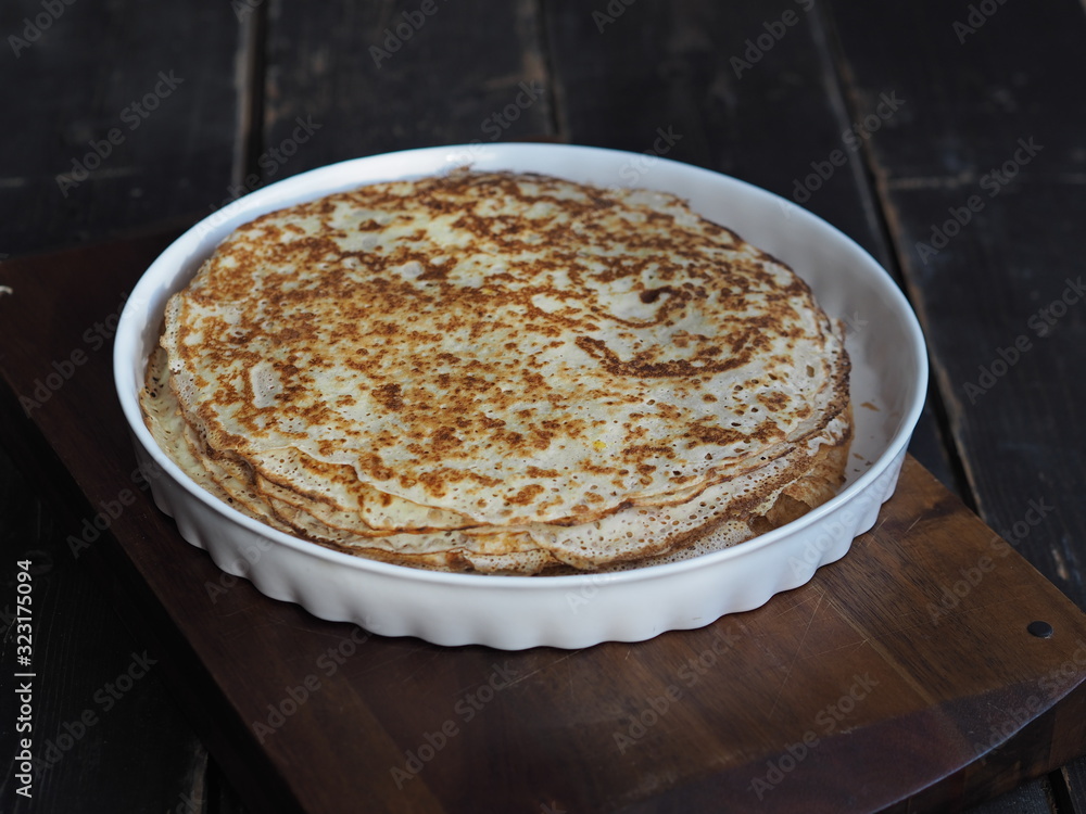 Maslenitsa. Hot pancakes laid on a plate. Festive background with artificial lighting. Selective focus. Place for text. Maslenitsa. Hot pancakes laid on a plate. Festive background with artificial lighting. Selective focus. Place for text.