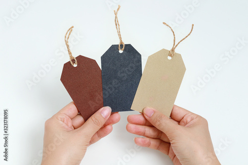 Hand holding blank gift box tags or sale shopping labels with rope. 