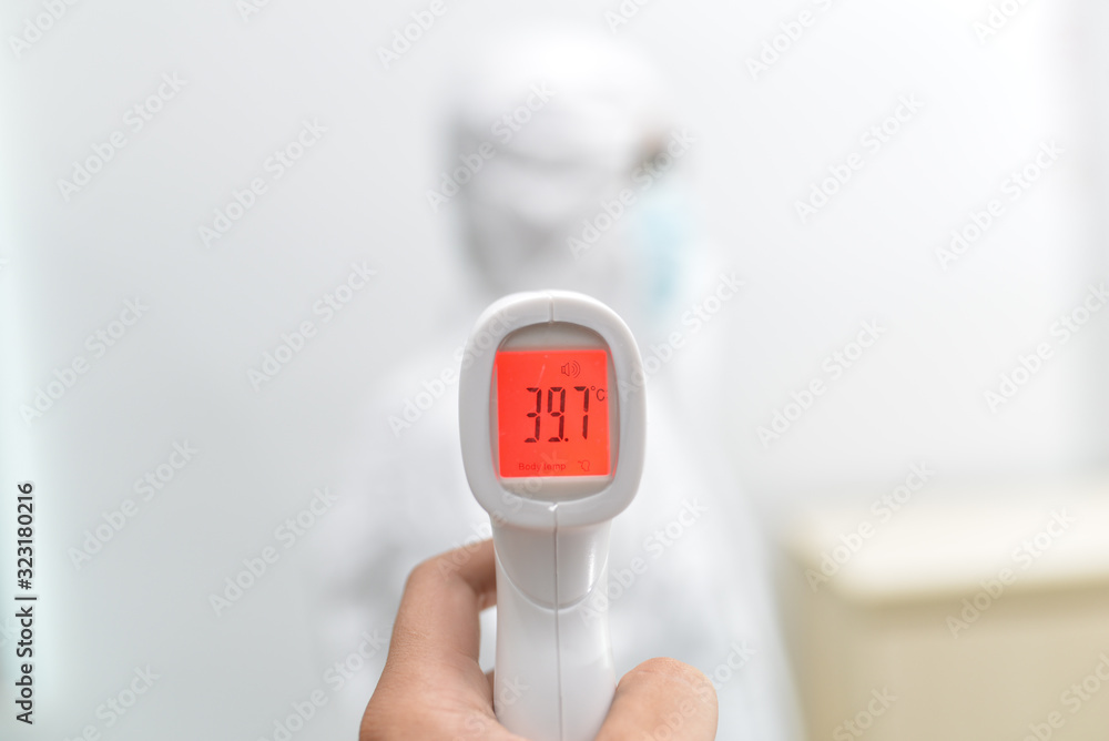 An Asian male doctor is measuring his body temperature with electronic thermometer before work to prevent the spread of the coronavirus outbreaks. The red color is high temperature, maybe he's sick An Asian male doctor is measuring his body temperature with electronic thermometer before work to prevent the spread of the coronavirus outbreaks. The red color is high temperature, maybe he's sick