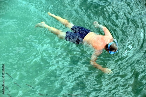 man in the ocean with a mask snorkeling watches fish