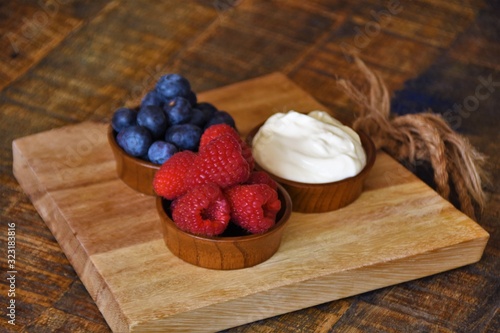 fresh ripe berries, raspberries, blueberries and yogurt in wooden rosettes