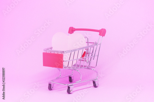 Shopping Cart and Pink heart on pink background with copy space - Shopping stores to buy Love Heart or Company for couples concept - Valentine Day 