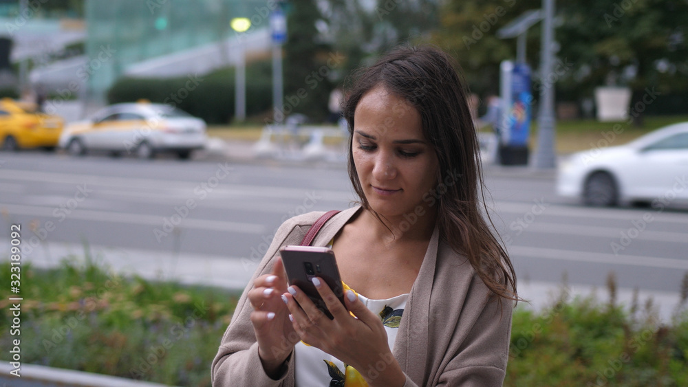 Attractive Woman using Mobile Phone by the Big Industrial Building near the road
