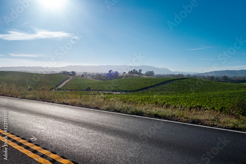 four lane highway with rolling farm. hills and btight sun in sky photo