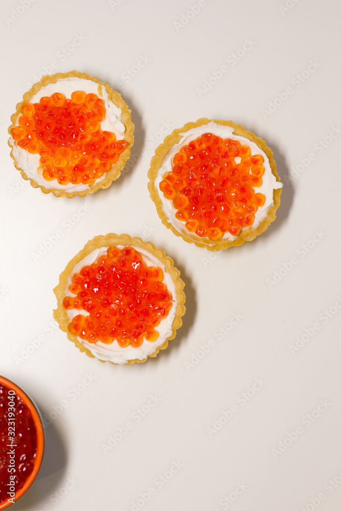 three tartlets with cream cheese and red caviar on a white background. the concept of a delicious Breakfast, buffet and snack. seafood dish. the view from the top. space for text. three tartlets with cream cheese and red caviar on a white background. the concept of a delicious Breakfast, buffet and snack. seafood dish. the view from the top. space for text.