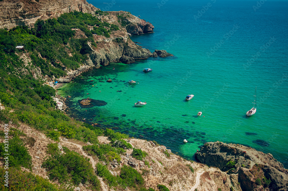 Stone Beach and Blue Lagoon with white yachts. Sea vacation. Summer season.