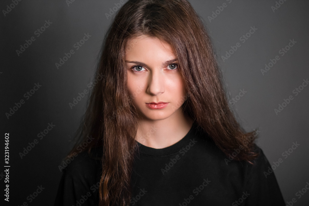 Portrait of a beautiful, young girl in black clothes with long hair. Studio photo, on a gray background. A model with clean skin. Portrait of a beautiful, young girl in black clothes with long hair. Studio photo, on a gray background. A model with clean skin.