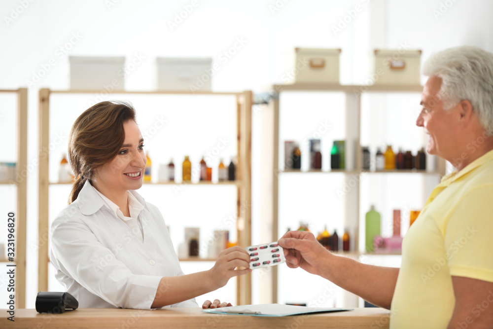 Fototapeta premium Pharmacist giving medicine to customer in drugstore