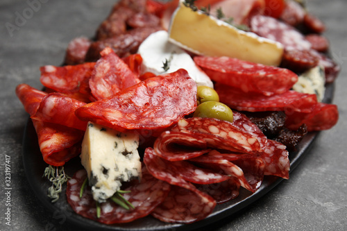 Tasty salami and other delicacies served on grey table, closeup