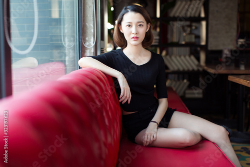 sexy woman sitting on red leather sofa,looking at camera. photo