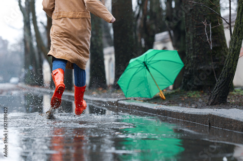 Woman in rubber boots running after umbrella outdoors on rainy day  closeup