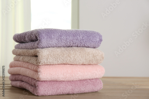 Stack of fresh towels on wooden table in bathroom, closeup