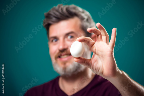 A portrait of bearded man holding egg in hand. People and food concept