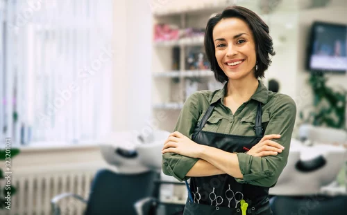 Fototapeta na wymiar Uśmiech profesjonalisty. Portret pięknej młodej fryzjerki stojącej ze skrzyżowanymi ramionami w pobliżu swojego miejsca pracy w salonie.