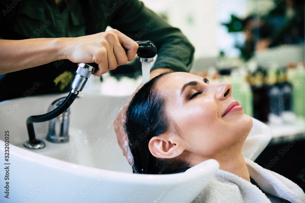 Naklejka premium True pleasure. Cropped shot of hairstylist washing hair of her female customer in premium hair salon.