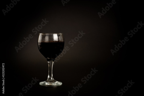 Glass with red wine shot on a dark background. Background for alcohol. Glassware for alcoholic beverages
