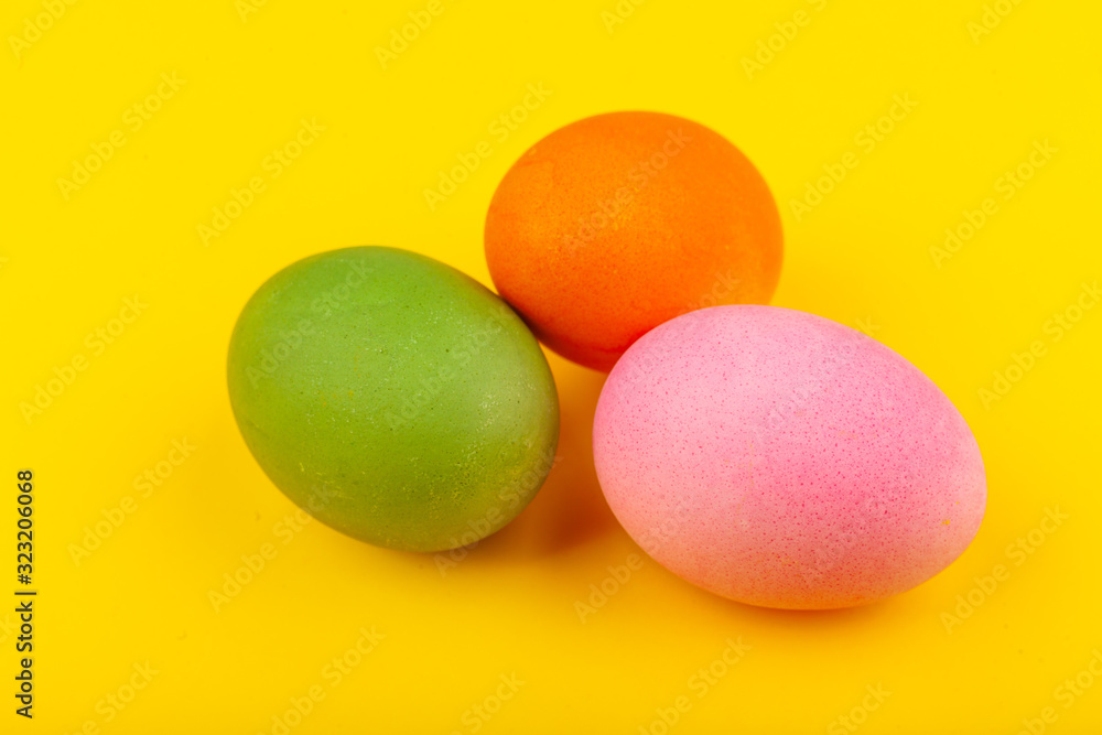 Colorful handmade Easter eggs. Top view of three eggs. Isolated on a yellow background. Preparing for Easter. Colorful handmade Easter eggs. Top view of three eggs. Isolated on a yellow background. Preparing for Easter.