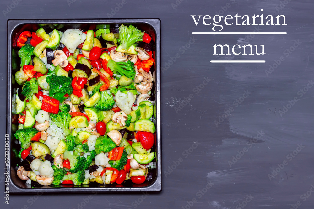 Stewed vegetables on a baking sheet on a table with text Vegetarian menu. Stewed vegetables on a baking sheet on a table with text Vegetarian menu.