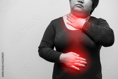 A Female have symptoms of burning sensation in the middle of the chest caused by acid reflux or Woman with fat Suffering From Acid Reflux Or Heartburn. black and white. fat, overweight and health care