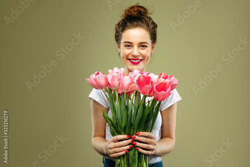 Young girl holding bouquet of pink tulips flower against green background