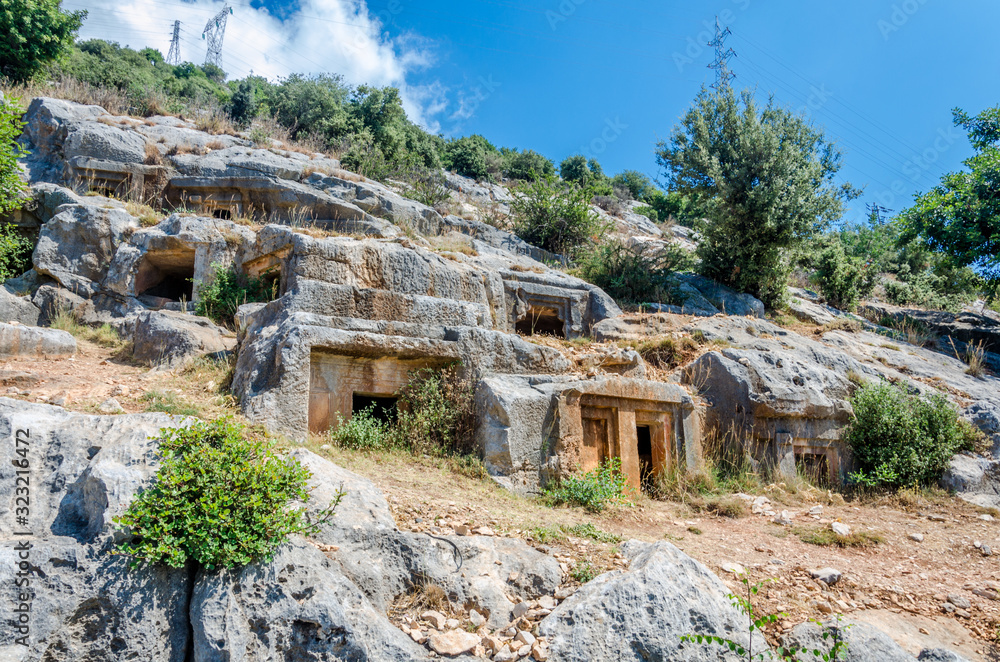 Ancient cemetery in the city of Limyra, Turkey. The entrance to the old concrete tomb in the rock. Excursion to the historical monument of architecture. Burial of ancestors closer to the sky
