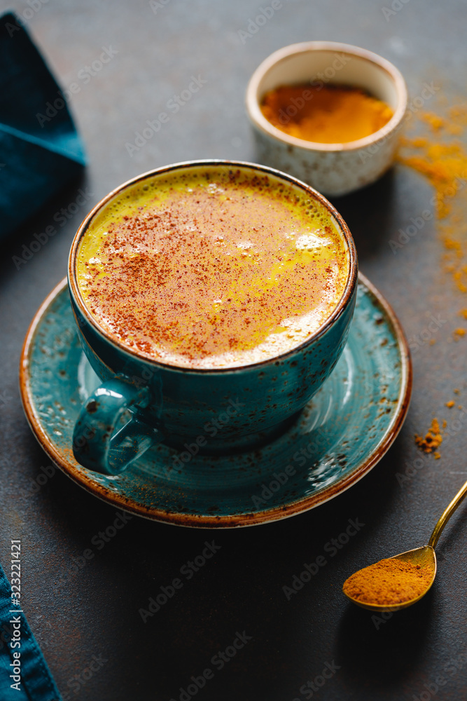 Closeup view of turmeric latte cup on a textured dark background. Closeup view of turmeric latte cup on a textured dark background.