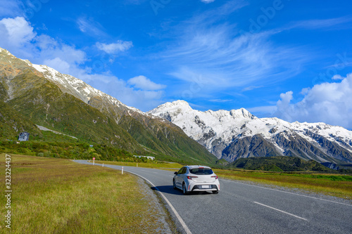 Cars run on highways in the morning with blue skies and clouds in summer. There are green grass beside the roads in Mount Cook National Park, Aoraki, New Zealand.