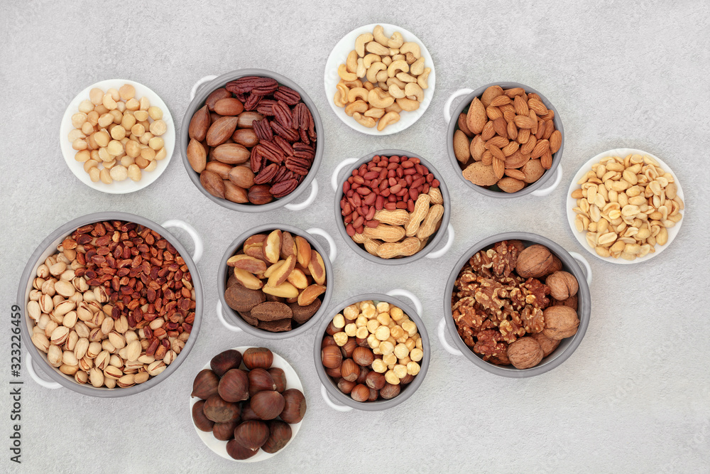 Dried nut health food collection suitable for a vegan and vegetarian diet high in protein, omega 3, antioxidants, minerals and vitamins. Flat lay on mottled grey background. Dried nut health food collection suitable for a vegan and vegetarian diet high in protein, omega 3, antioxidants, minerals and vitamins. Flat lay on mottled grey background.