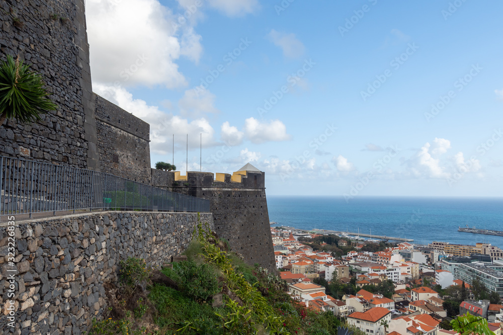 Naklejka premium The São João Baptista fortres in foreground and part of the town and harbor with sea and blue sky with some clouds in background