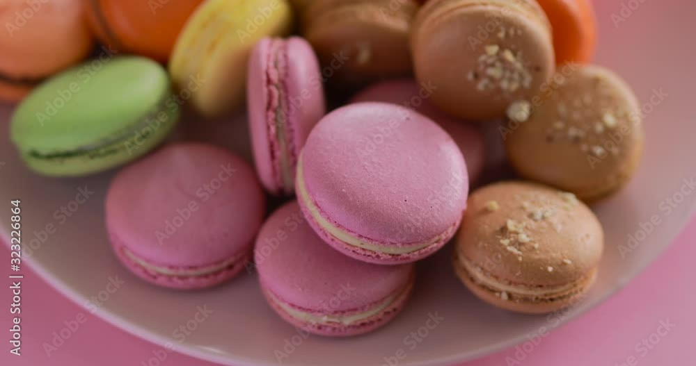 Female hand put a one pink macaroon into the big macaron collection Female hand put a one pink macaroon into the big macaron collection