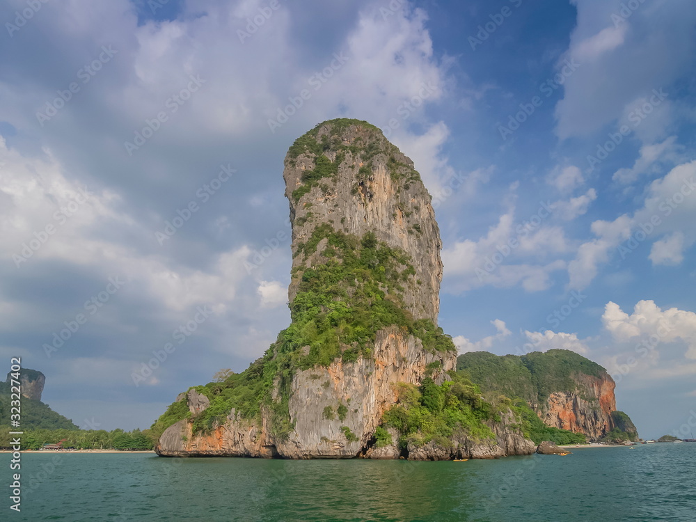 view of high cliff rock mountain in the sea with cloudy and blue sky background, Railay Bay, Krabi, southern of Thailand.