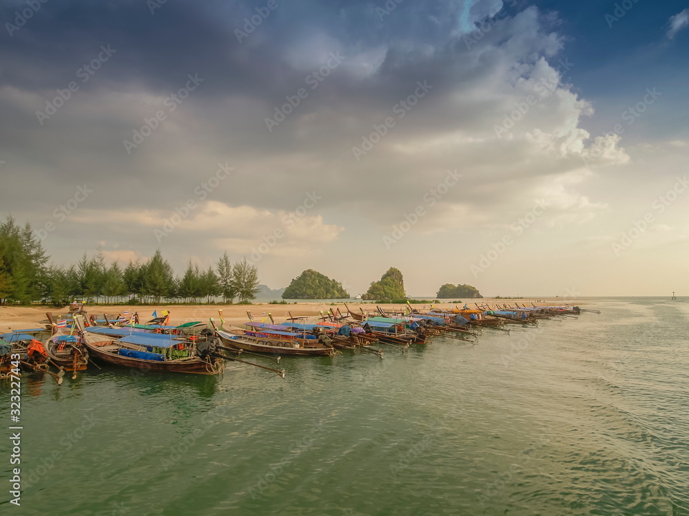 sea view evening of many long-tail boats floating seaside with green trees and cloudy sky background, Ao Nang Pier, Krabi, southern of Thailand.