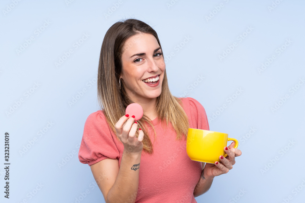 Φωτογραφία Young blonde woman over isolated blue background holding colorful French macaron