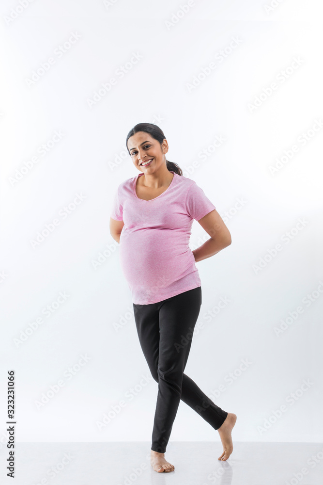 Cheerful pregnant woman standing with her legs crossed and smiling. Cheerful pregnant woman standing with her legs crossed and smiling.