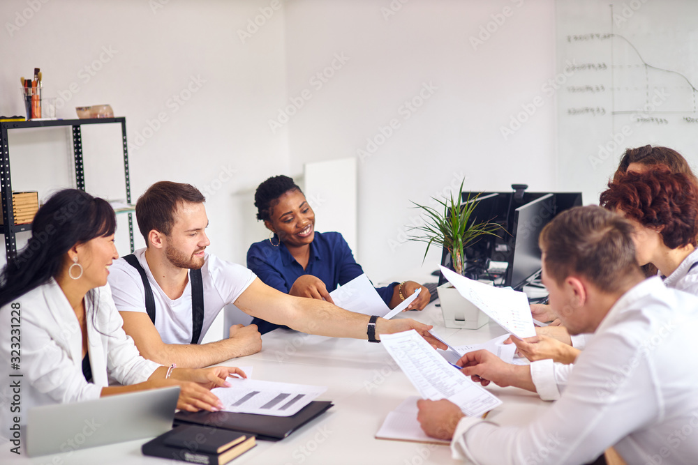 Creation of new business idea by multiethnic group sitting in meeting office, white interior background. Wearing formal wear, holding papers. Asian, caucasian, african partnership Creation of new business idea by multiethnic group sitting in meeting office, white interior background. Wearing formal wear, holding papers. Asian, caucasian, african partnership