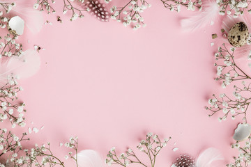 Happy Easter frame with flowers, feathers and egg shells on pink background