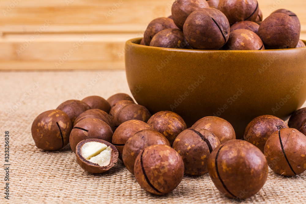 Macadamia nuts closeup on burlap. Healthy eating concept, the prevention of heart disease, cosmetology. Macadamia nuts background texture. Macadamia nuts closeup on burlap. Healthy eating concept, the prevention of heart disease, cosmetology. Macadamia nuts background texture.