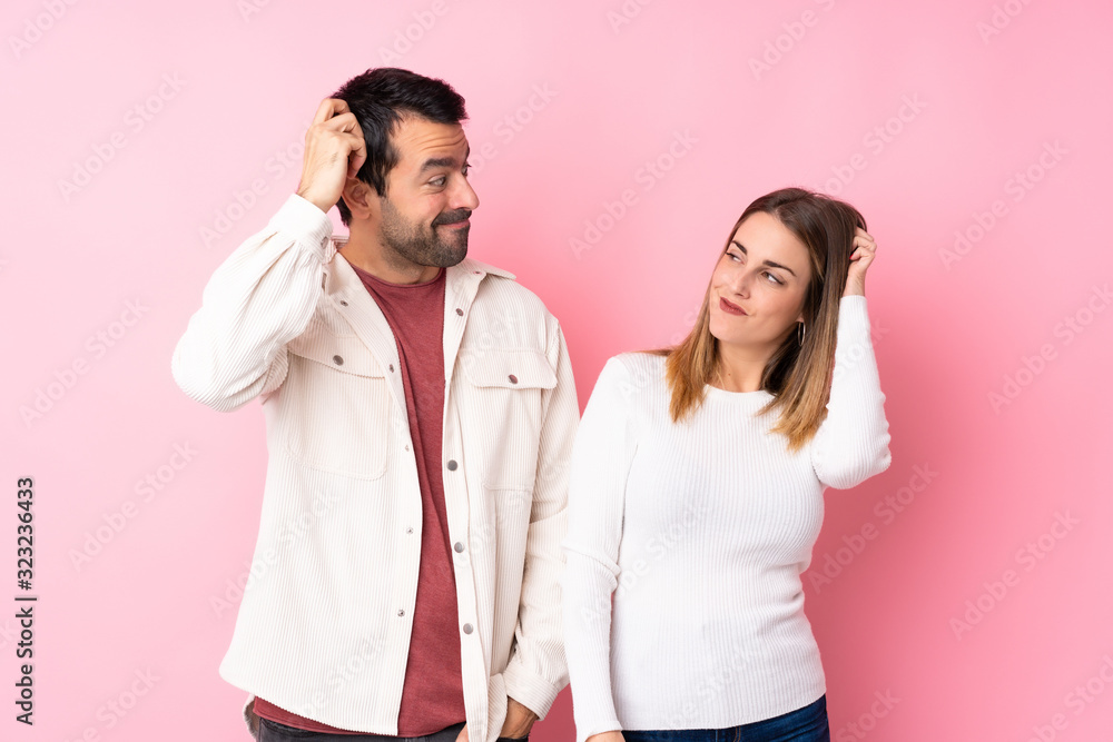 Couple in Valentine Day over isolated pink background having doubts while scratching head Couple in Valentine Day over isolated pink background having doubts while scratching head