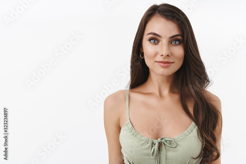 Waist-up portrait beautiful caucasian female brunette in green cute dress, smiling and looking camera, feeling confident, dress and put on evening makeup for going out romantic date, white background