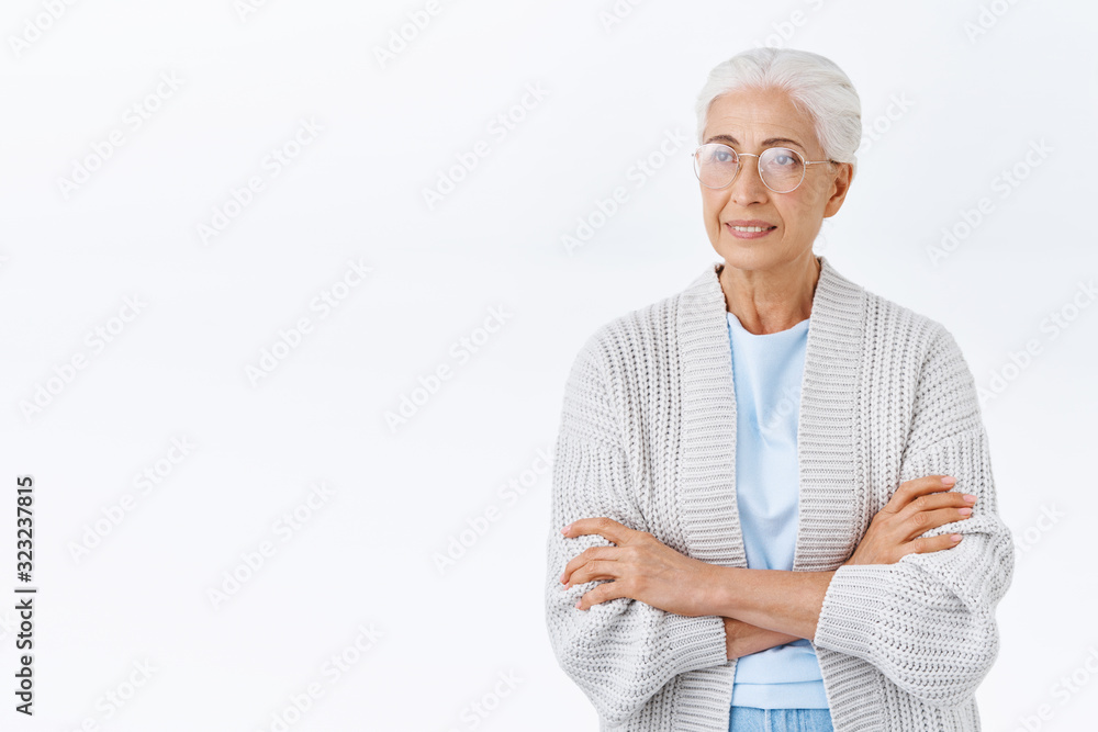 Thoughtful elderly woman in glasses, warm comfortable plaid cadrigan, cross arms chest, smiling and looking left interested, entertained, watching tv show or daydreaming, thinking about family Thoughtful elderly woman in glasses, warm comfortable plaid cadrigan, cross arms chest, smiling and looking left interested, entertained, watching tv show or daydreaming, thinking about family