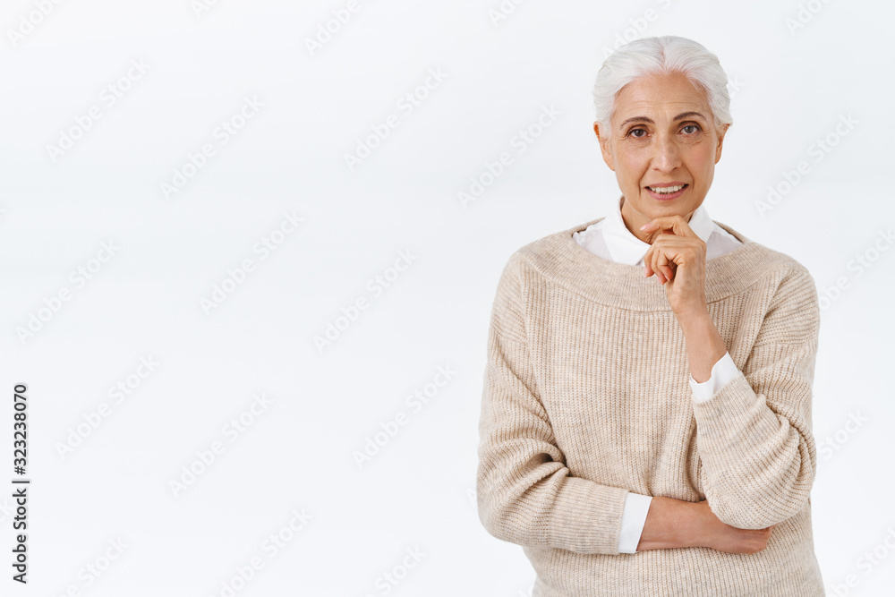Curious, good-looking senior lady, old woman in trendy elegant outfit, sweater over blouse, touching chin and look camera intrigued, smiling with interest, standing thoughtful, white background Curious, good-looking senior lady, old woman in trendy elegant outfit, sweater over blouse, touching chin and look camera intrigued, smiling with interest, standing thoughtful, white background