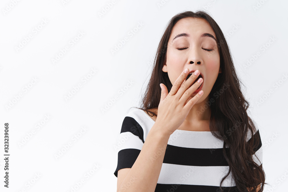 Girl is not morning person. Cute and silly young sleepy asian woman in striped t-shirt, yawning, cover opened mouth and close eyes, tired or falling asleep from boredom, standing white background Girl is not morning person. Cute and silly young sleepy asian woman in striped t-shirt, yawning, cover opened mouth and close eyes, tired or falling asleep from boredom, standing white background